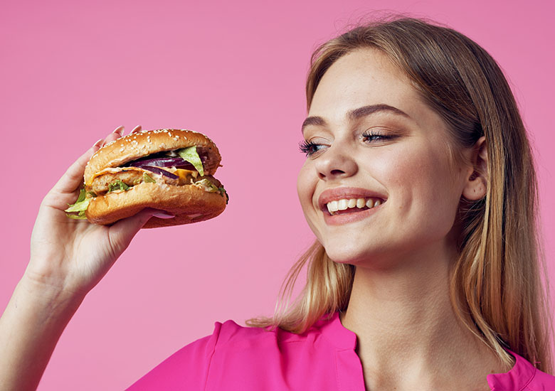 Smiling,Pretty,Woman,In,Pink,Shirt,With,A,Hamburger,In